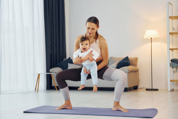 Teaching fitness. Mother with her little daughter is at home together. - Fotó, kép