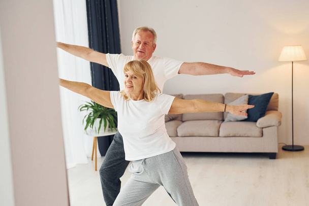 Sportive exercises. Senior man and woman is together at home. - Photo, image