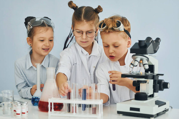 Test tubes with colorful liquid. Children in white coats plays a scientists in lab by using equipment. - Photo, image