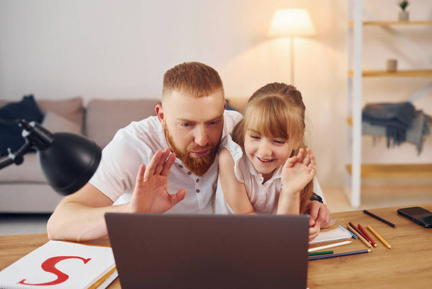 Online learning. Father with his little daughter is at home together. - Fotó, kép