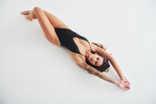 Lying down on the ground. Beautiful seductive sporty woman with sexy body is posing in the studio. - Foto, Imagem