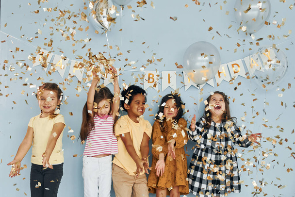 Balony i konfetti. Dzieci na uroczystości urodzinowe w pomieszczeniach zabawy razem. - Zdjęcie, obraz