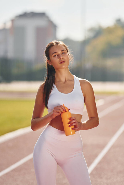 Тримає пляшку з водою. Молода жінка в спортивному одязі займається на відкритому повітрі
. - Фото, зображення