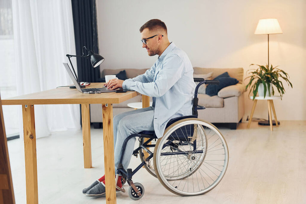 Smart freelance worker. Disabled man in wheelchair is at home. - Fotografie, Obrázek