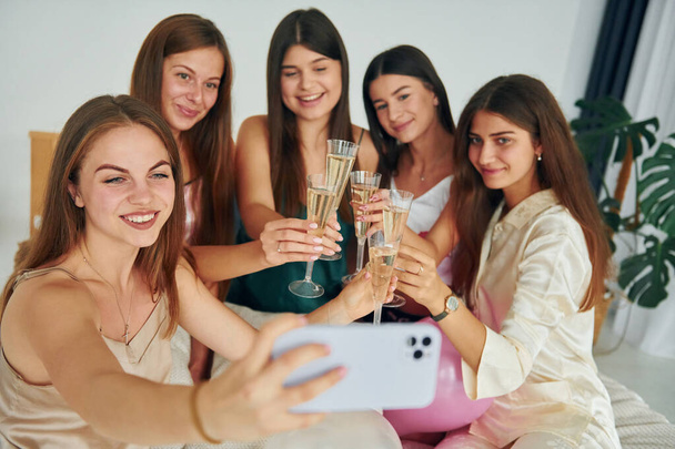 Holding glasses with drink. Group of happy women that is at a bachelorette party. - Foto, imagen