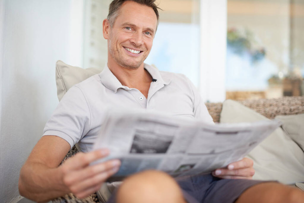 The more you read the more youll know, the more you learn more places youll go. A handsome mature man sitting comfortably at home reading the newspaper - Foto, imagen