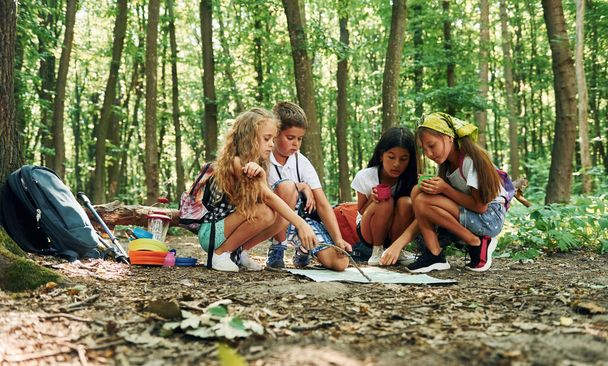 Sitting on the ground. Kids strolling in the forest with travel equipment. - Foto, Imagen