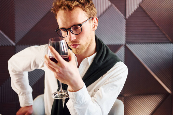 Man in glasses sits by the table. Indoors of new modern luxury restaurant. - 写真・画像