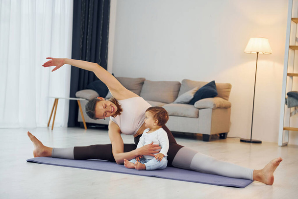 Doing fitness together. Mother with her little daughter is at home together. - Φωτογραφία, εικόνα