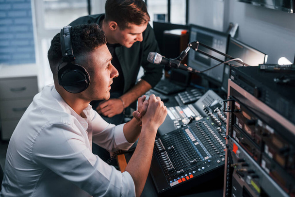 Conception of teamwork. Two guys is indoors in the radio studio is busy by broadcast. - Fotoğraf, Görsel