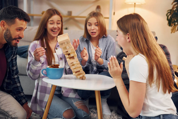 Wooden tower has fallen. Group of friends have party indoors together. - Photo, image