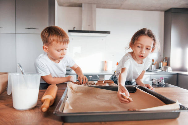 Brother and sister helping each other. Little boy and girl preparing Christmas cookies on the kitchen. - Foto, Bild