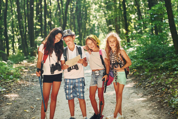 Front view. Kids strolling in the forest with travel equipment. - Photo, image