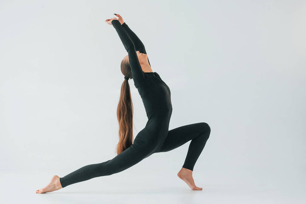 Healthy person. Young woman in sportive clothes doing gymnastics indoors. - Fotó, kép