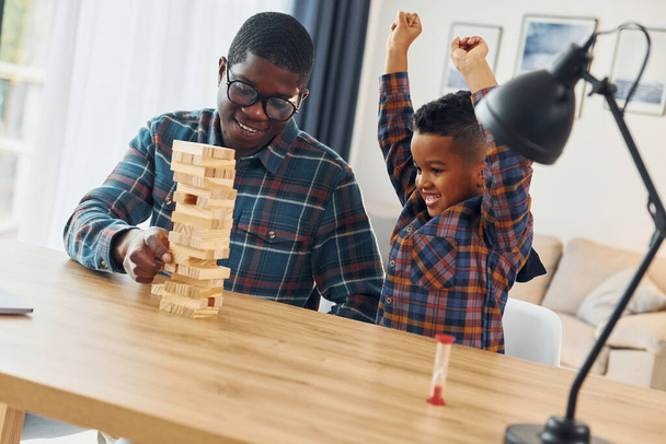 Playing bricks game. African american father with his young son at home. - Fotó, kép