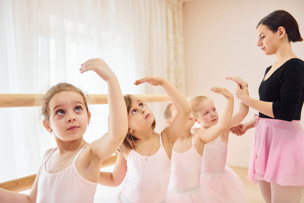 Woman teaches dance moves. Little ballerinas preparing for performance. - Foto, afbeelding