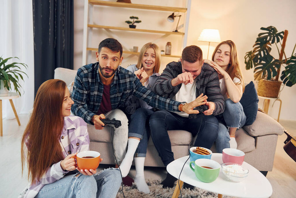 Playing video game. Group of friends have party indoors together. - Φωτογραφία, εικόνα