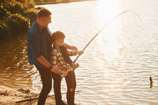 Conception of hobbies. Father and son on fishing together outdoors at summertime. - Fotó, kép