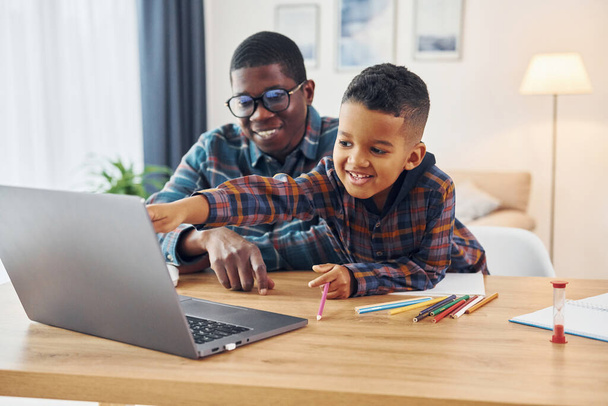 With laptop on table. African american father with his young son at home. - Photo, Image