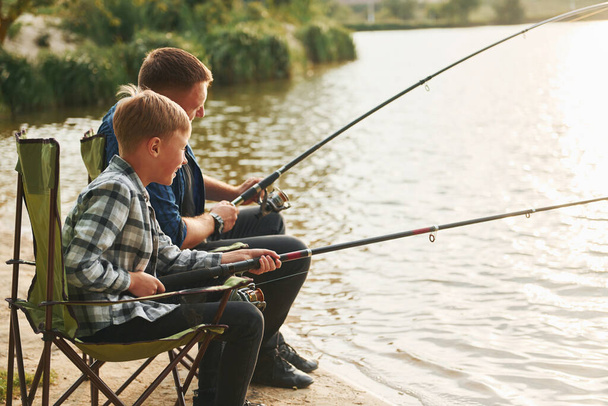 Resting and having fun. Father and son on fishing together outdoors at summertime. - Fotó, kép