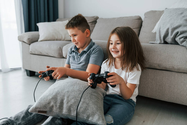 Playing videogames. Kids having fun in the domestic room at daytime together. - Zdjęcie, obraz