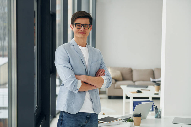 Young guys in glasses and formal clothes standing in the office. - 写真・画像