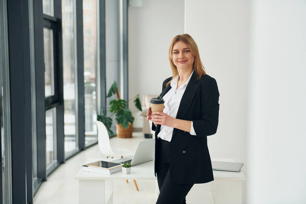 Woman in formal clothes is indoors in the modern office at daytime. - Foto, Imagen