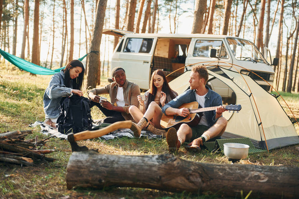 Camp and car. Group of young people is traveling together in the forest at daytime. - Foto, Imagen