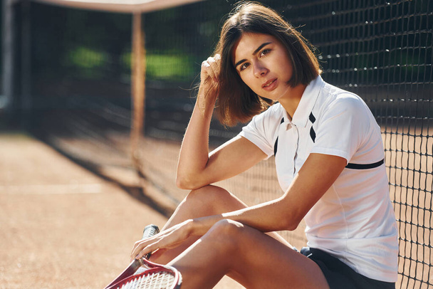 Looking at the camera. Female tennis player is on the court at daytime. - Foto, Imagen