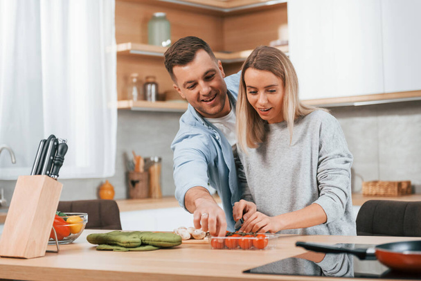 Cute people. Couple preparing food at home on the modern kitchen. - Foto, afbeelding
