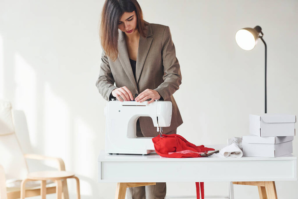 Seamstress working in the office. Young woman in formal clothes is indoors. Conception of style. - Foto, afbeelding