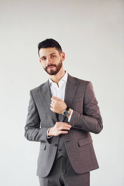Posing for a camera against white background. Young stylish businessman in suit indoors. - Zdjęcie, obraz