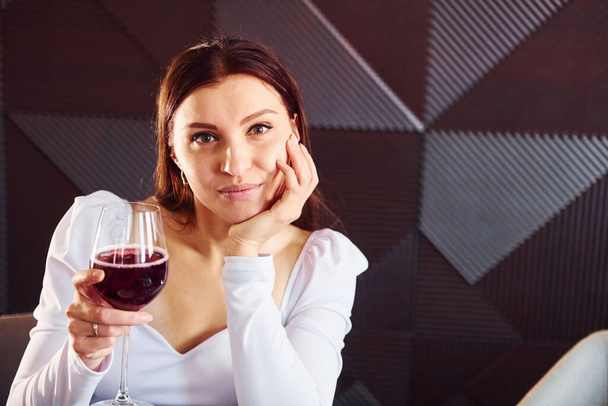 Beautiful woman sits by table. Indoors of new modern luxury restaurant. - 写真・画像