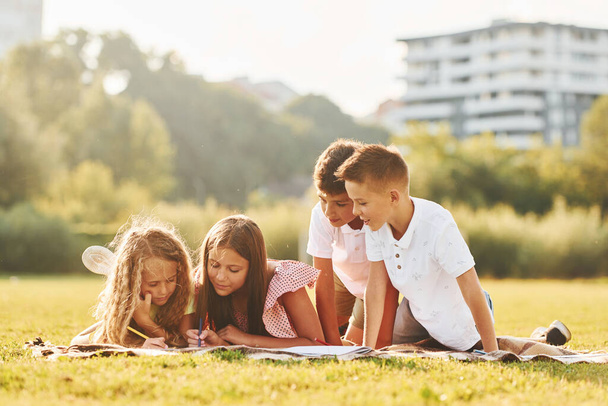 Drawing pictures. Group of happy kids is outdoors on the sportive field at daytime. - Fotoğraf, Görsel