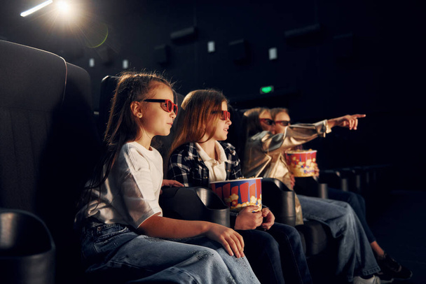 Mit Popcorn. Gruppe von Kindern sitzt im Kino und schaut gemeinsam Film. - Foto, Bild