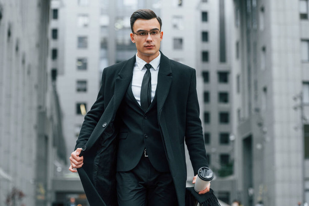 Walking forward. Businessman in black suit and tie is outdoors in the city. - Fotó, kép