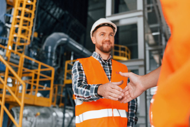 Making handshake with customer. Construction worker in uniform is in the factory. - Foto, immagini