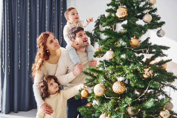 Decorating christmas tree. Family celebrating new year with their children at home. - Foto, imagen