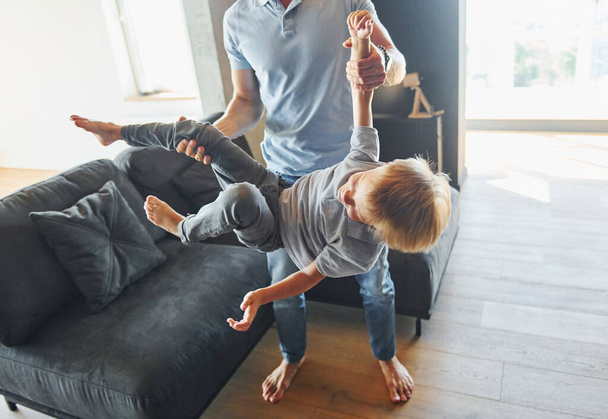 Man holding boy and having fun. Father and son is indoors at home together. - Foto, Bild