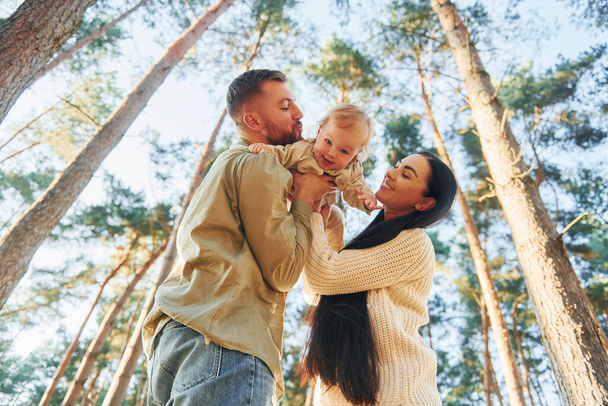 View from below. Happy family of father, mother and little daughter is in the forest. - Valokuva, kuva