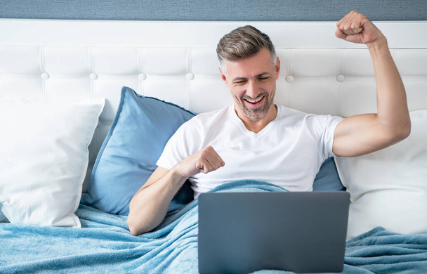 mature man working on laptop in bed. success. - Fotografie, Obrázek