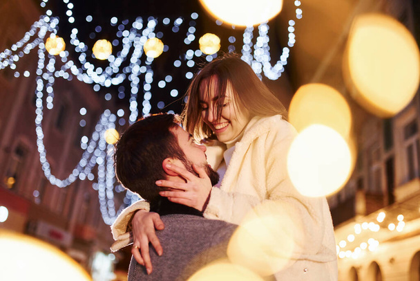 Embracing each other. Happy young couple celebrating New year outdoors on the street. - 写真・画像
