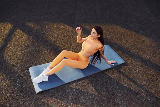 Resting on yoga mat. Young woman in sportswear have fitness session outdoors. - Foto, immagini