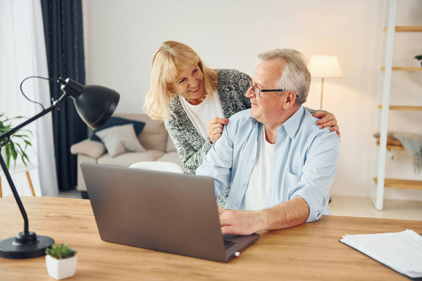 Using laptop. Senior man and woman is together at home. - Foto, imagen