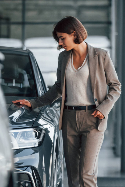 Woman is indoors near brand new automobile indoors. - Fotoğraf, Görsel