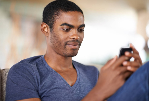 Тримайтеся за хорошого друга. красивий молодий чоловік використовує свій мобільний телефон, коли охолоджує вдома
 - Фото, зображення