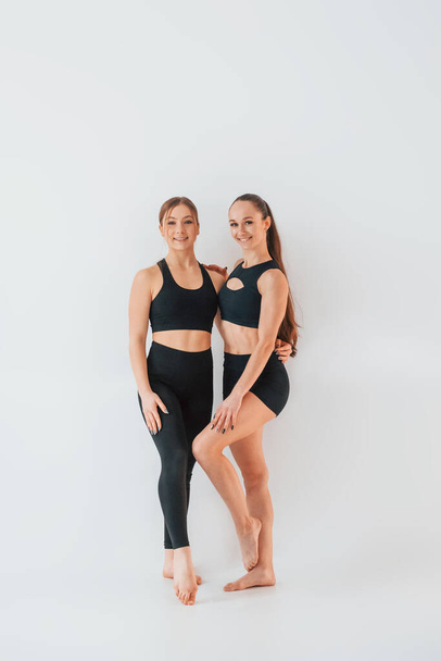 Two young women in sportive clothes is together indoors against white background. - Fotografie, Obrázek
