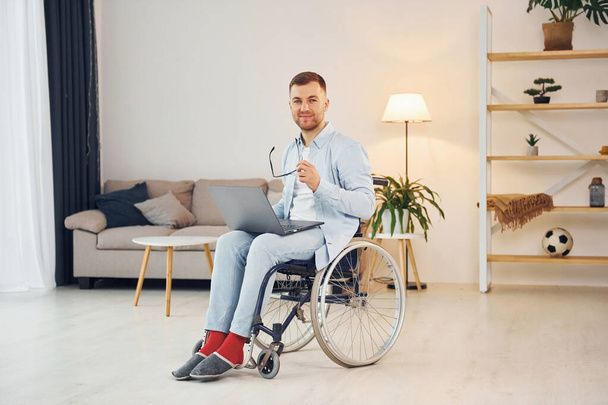 Cheerful disabled man in wheelchair is at home. - Φωτογραφία, εικόνα