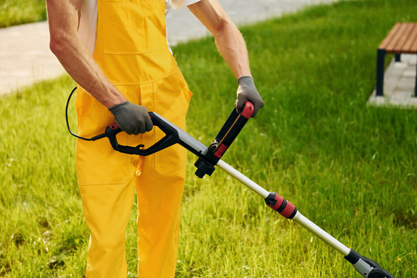Close up view. Man cut the grass with lawn mover outdoors in the yard. - Foto, afbeelding