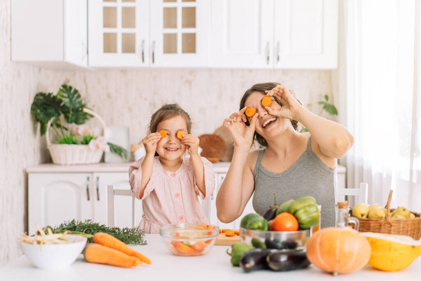Mom and daughter fooling around with vegetables together. - Photo, Image